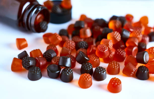 Gummies de compléments alimentaires colorés renversés à côté d’un flacon