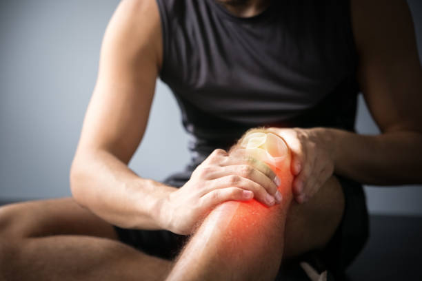 Homme tenant son genou souffrant d'une inflammation articulaire, illustration de la douleur musculaire après le sport et besoin de récupération physique naturelle.