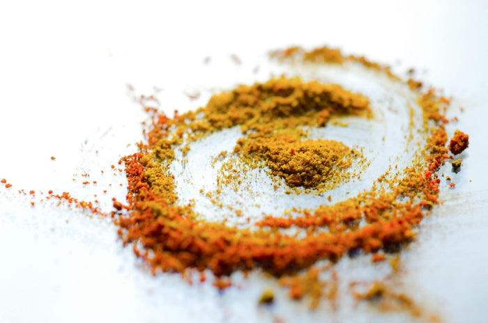 gros plan de poudre de curcuma jaune et orange formant un cercle sur une surface réfléchissante.