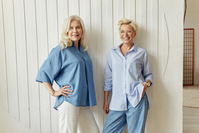Deux femmes d’âge mûr souriantes dans un intérieur lumineux, illustrant la préménopause et le bien-être féminin