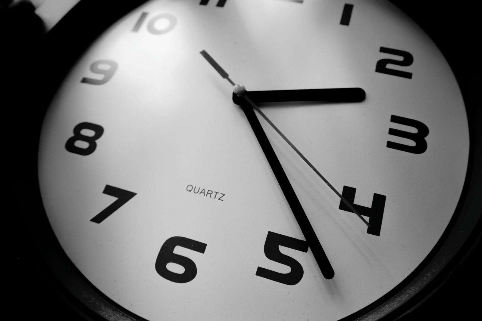 Gros plan en noir et blanc sur une horloge analogique indiquant environ 2 h 25.