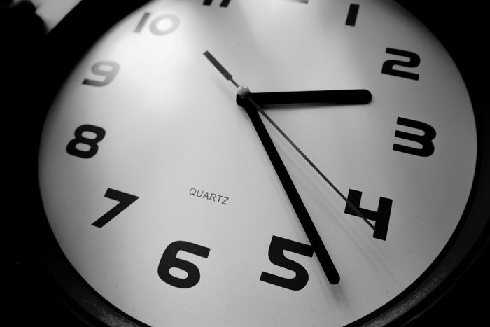 Gros plan en noir et blanc sur une horloge analogique indiquant environ 2 h 25.