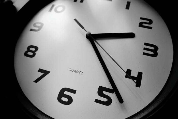 Gros plan en noir et blanc sur une horloge analogique indiquant environ 2 h 25.