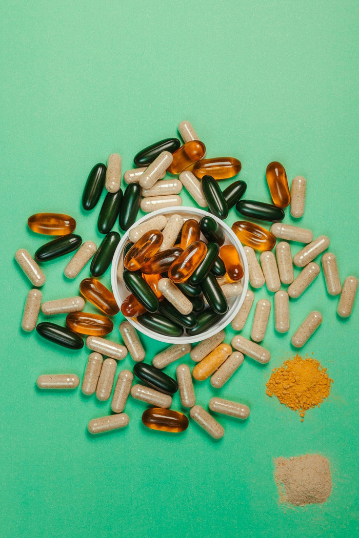 Vue de dessus de compléments alimentaires sous forme de gélules, capsules molles et poudres de curcuma et d'arginine sur un fond vert