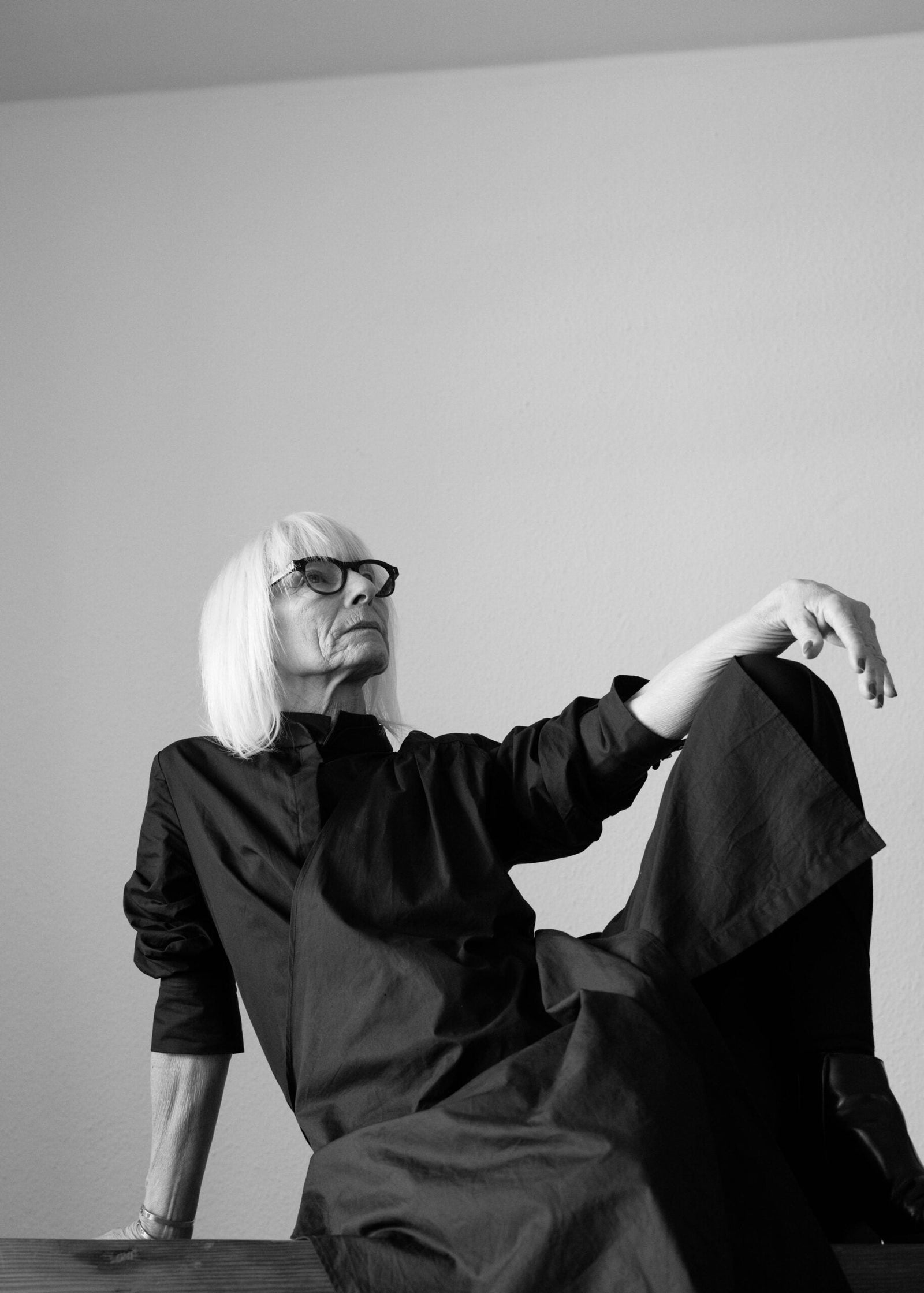 Femme mature en noir et blanc, assise avec une posture élégante et contemplative, illustrant les changements du corps et les signaux de l’inflammation silencieuse après 40 ans